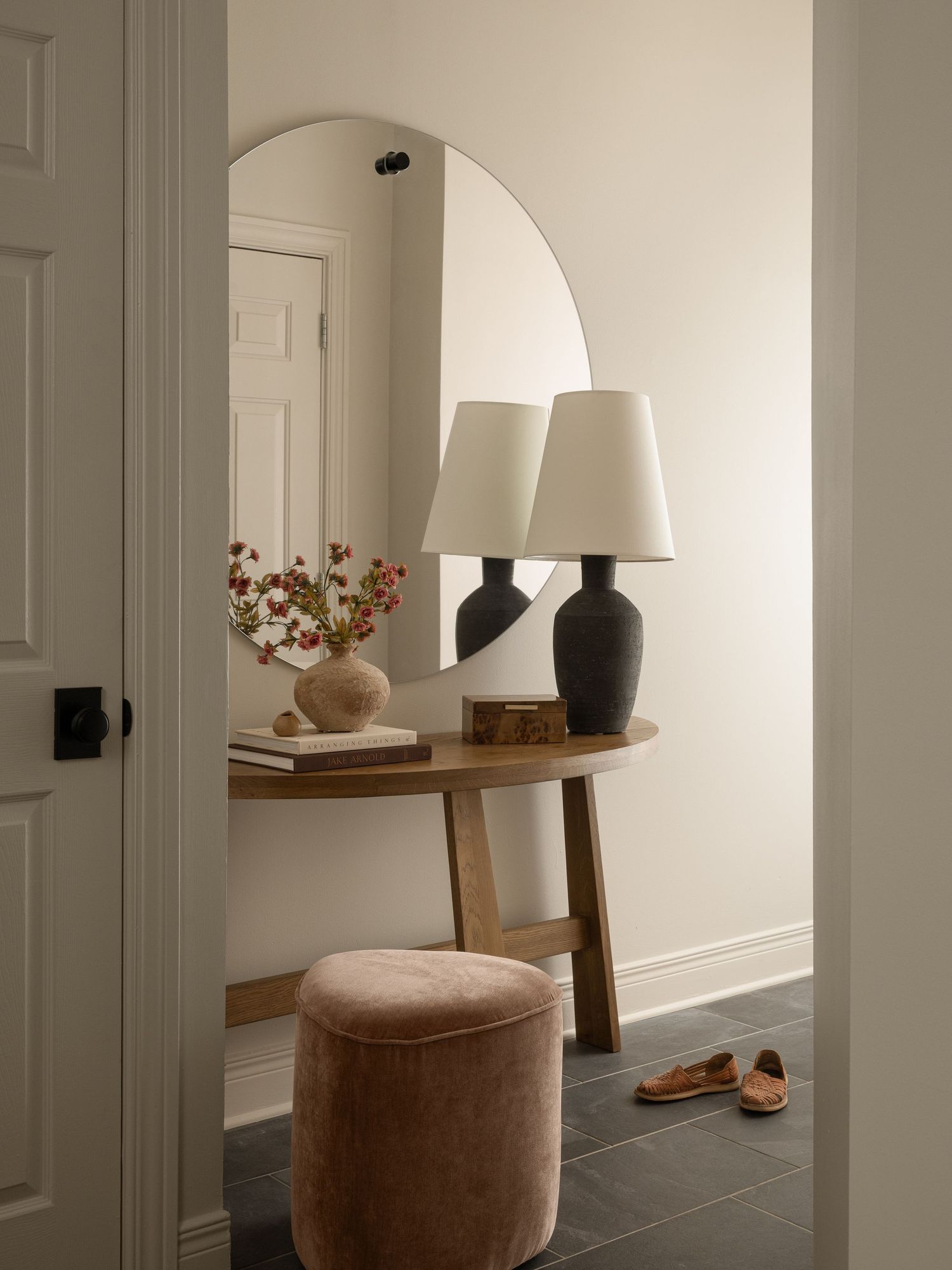 A cozy modern lighting showroom with brown sofa, curved chair, large dome pendant light, and stone accent wall.