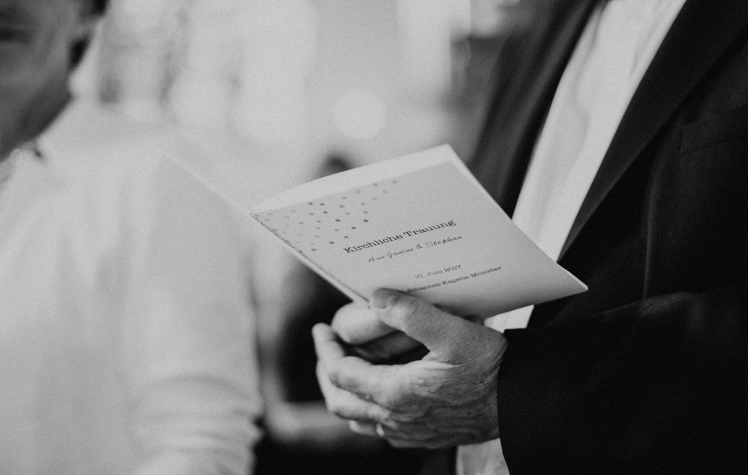 Hochzeitsgast hält ein Buch in den Händen. Schwarz-Weiss Fotografie