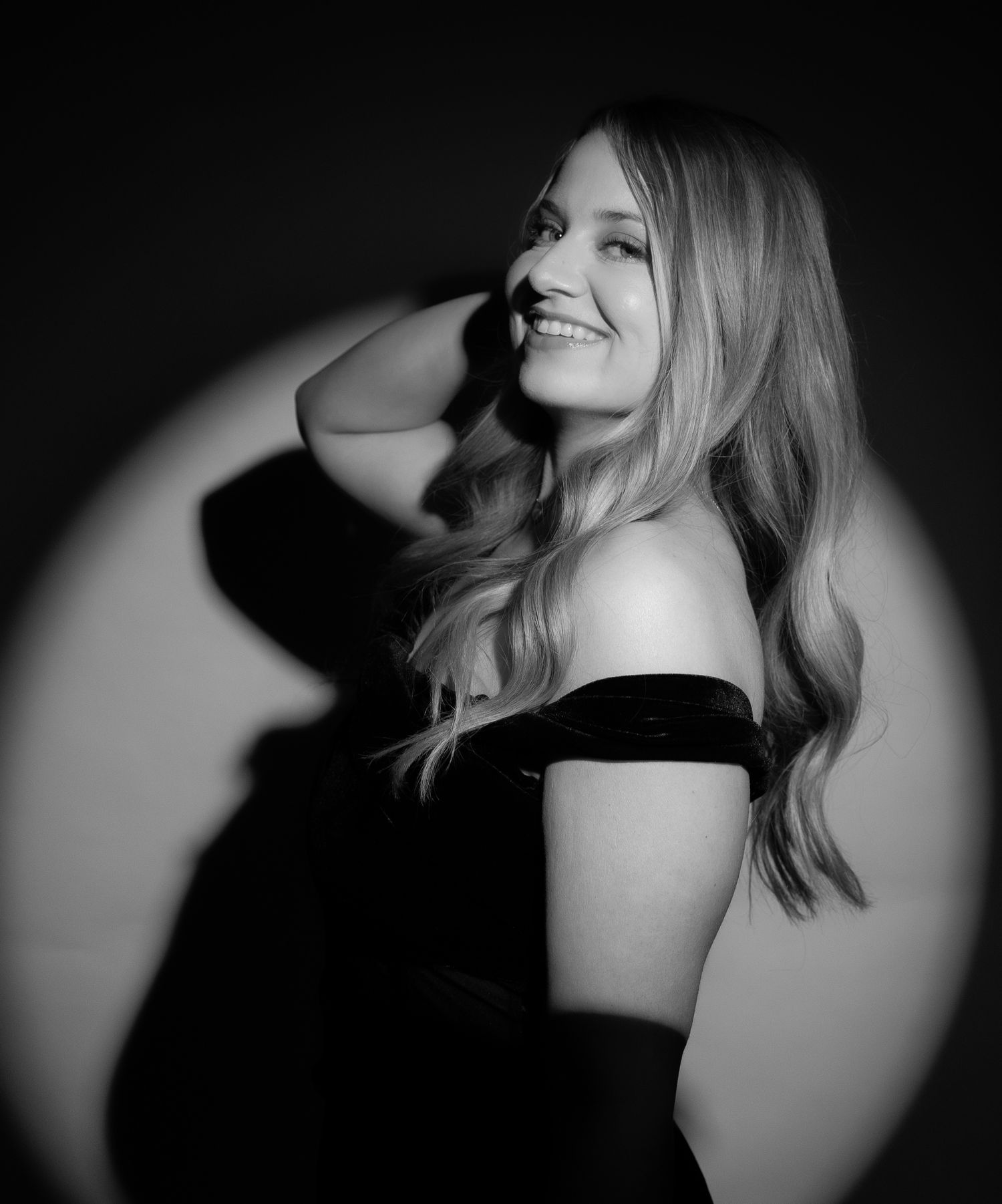 Woman smiling in black and white photo during their birthday spotlight session in a logan UT photo studio.