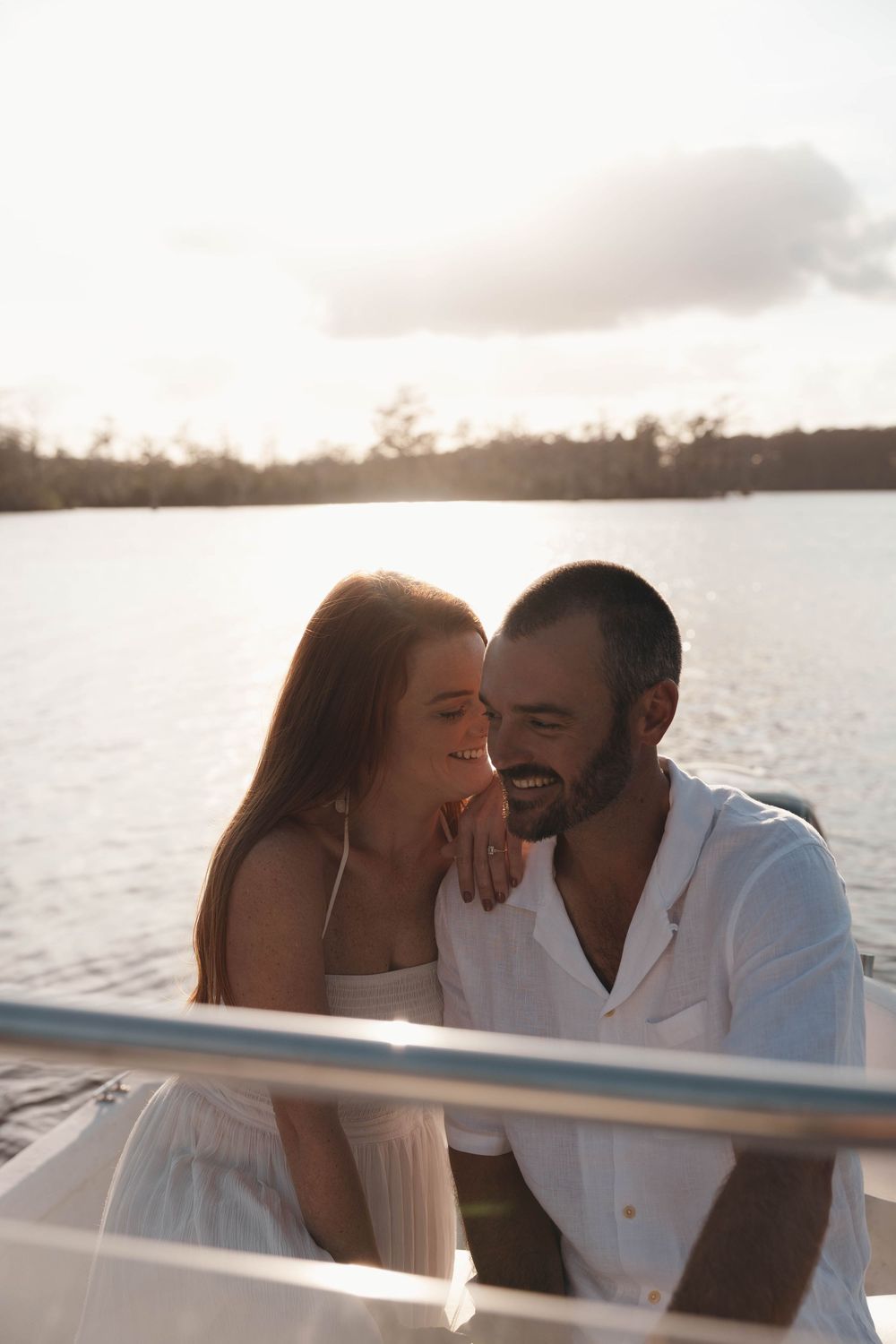Couple embracing in a small boat during a romantic engagement session on the Pasquotank River in Elizabeth City, North Carolina.