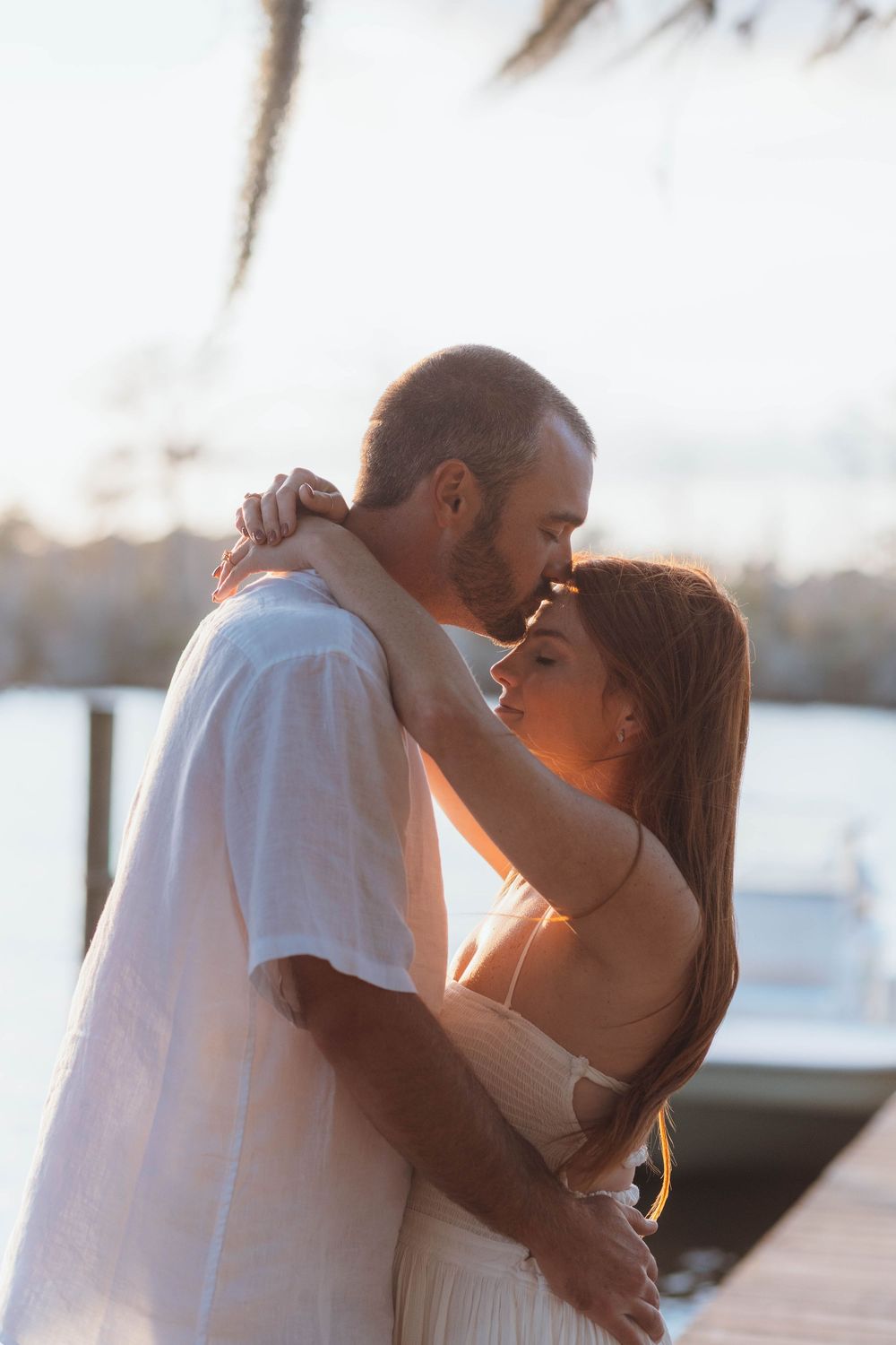 Couple embracing during a romantic engagement session on the Pasquotank River in Elizabeth City, North Carolina.