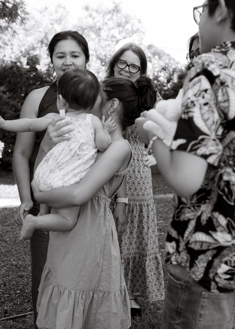 Small group of people gathered outdoors in black and white photograph having a casual interaction.