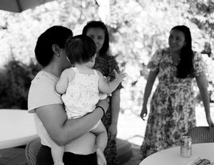 People dance together at an outdoor party with trees and natural lighting in the background.