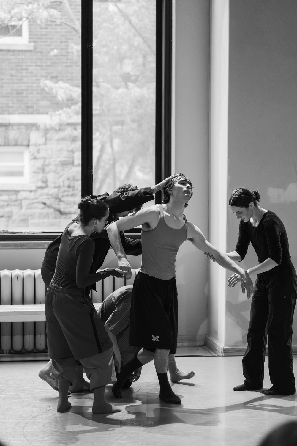 A sequence of contemporary dancers performing fluid movements in a bright studio space with large windows.