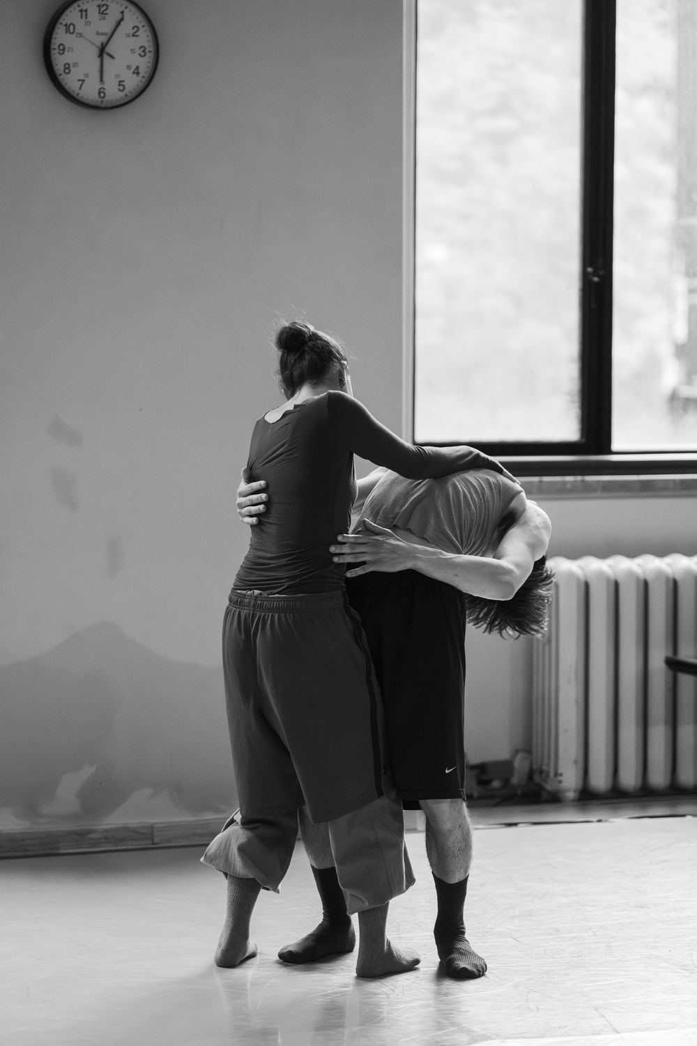 Black and white photo sequence showing dancer performing graceful movements in an empty dance studio with windows.
