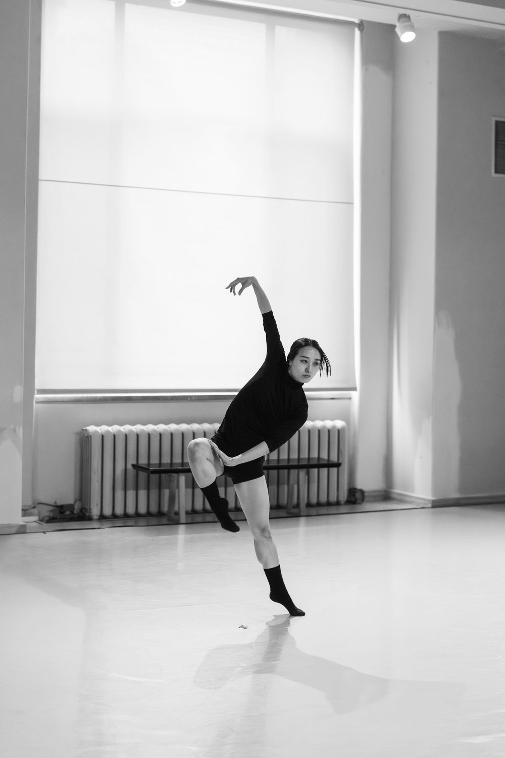 Four black and white photos show a modern dance sequence with a performer in mid-motion against a light studio space.
