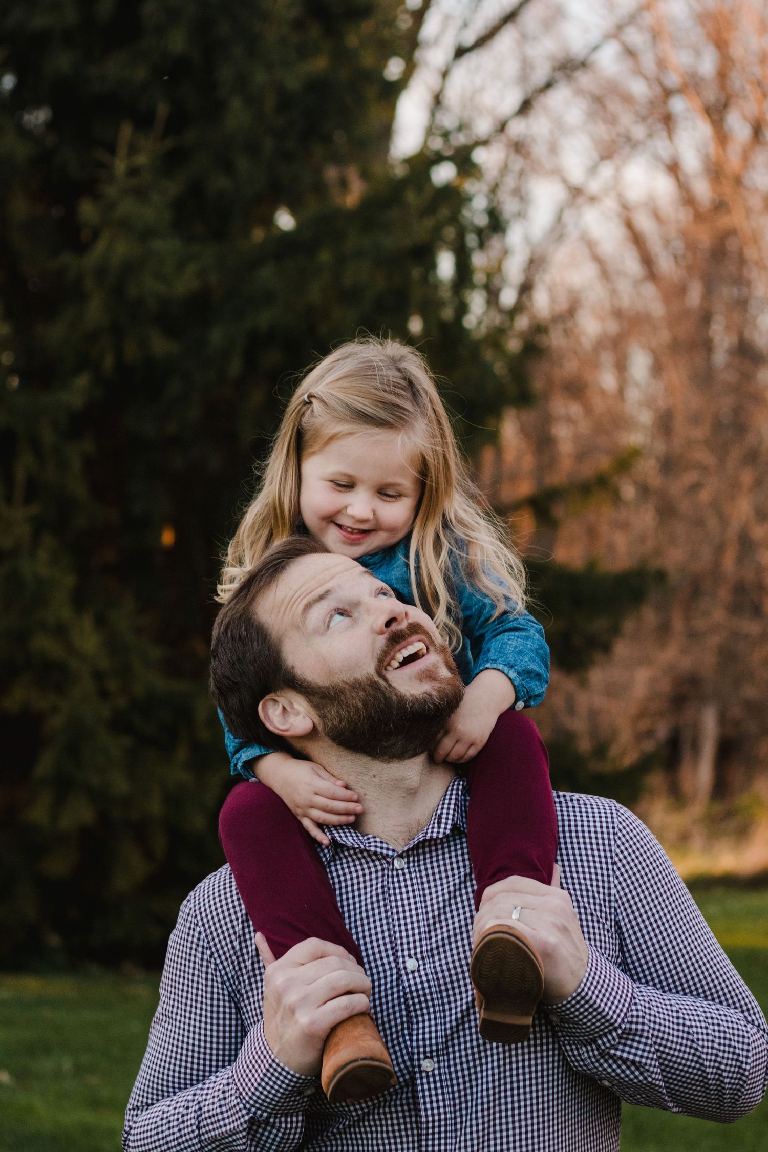 Daughter sitting on father's shoulders smiling during lifestyle family photography session - South Lyon, Michigan Family Photographer.