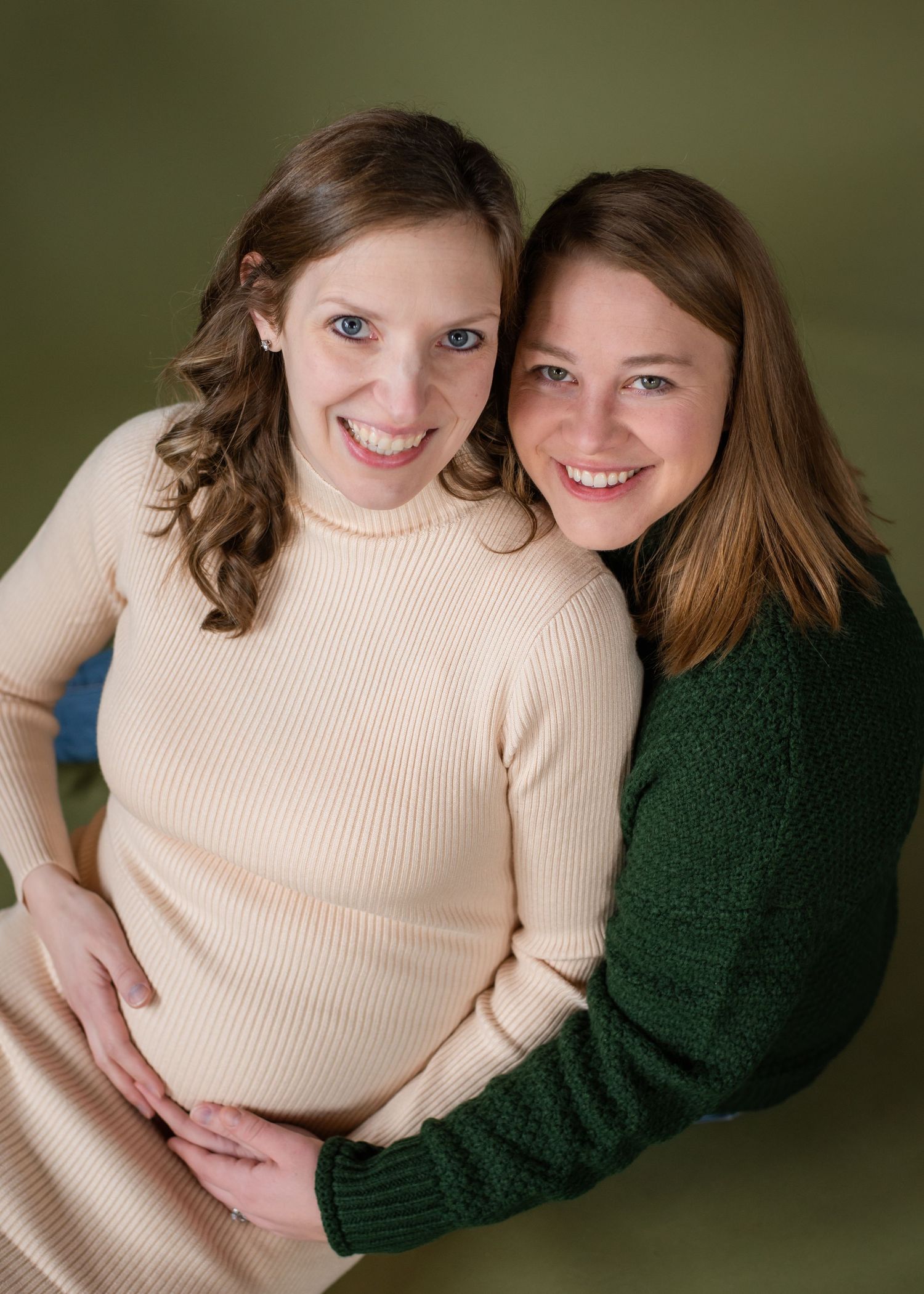 Two people wearing contrasting beige and green sweaters pose together in an intimate portrait series.