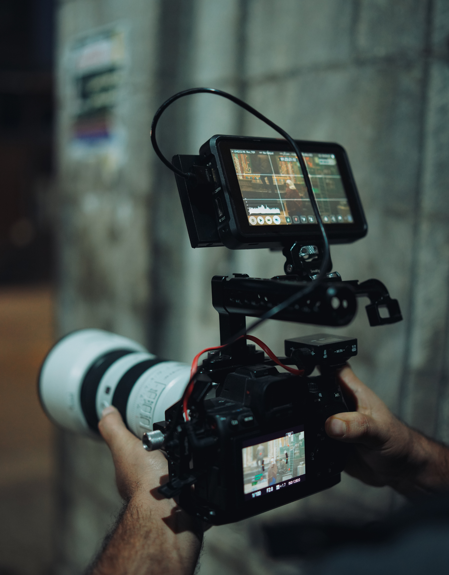 Professional camera setup with external monitor and telephoto lens mounted on a stabilizer rig.