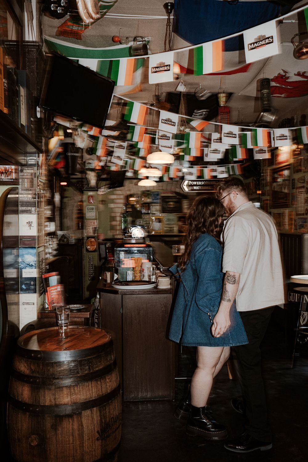A dimly lit bar interior with wooden barrels and hanging decor visible in a series of connected photographs.