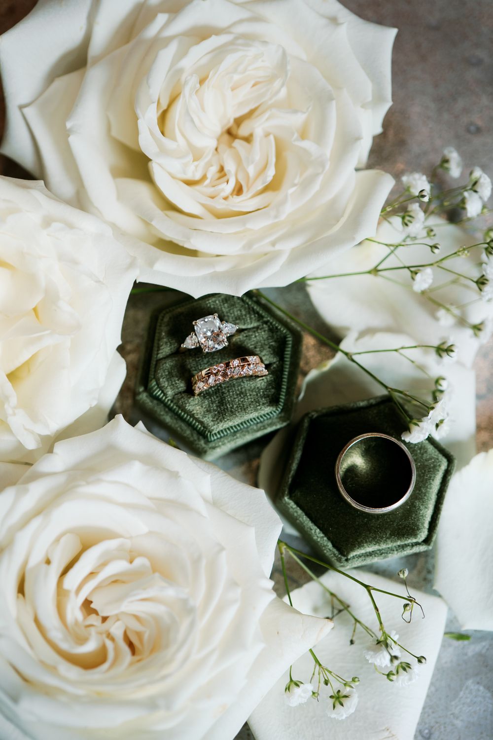 White roses and a green velvet ring box create an elegant wedding detail arrangement with delicate baby's breath accents.