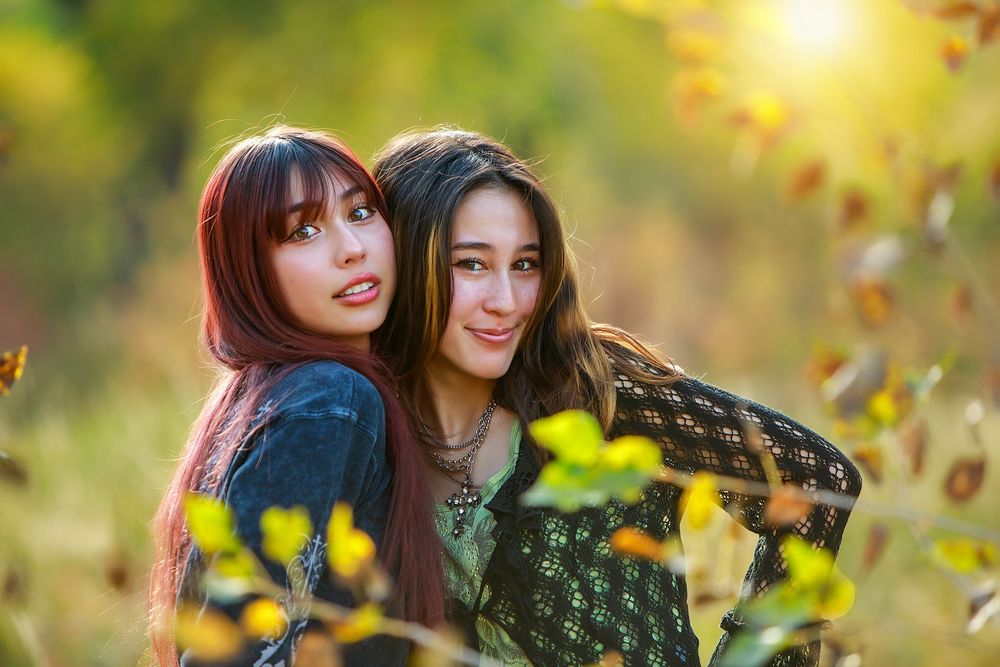 Two friends enjoying a sunny autumn day outdoors with golden leaves and warm lighting in the background.