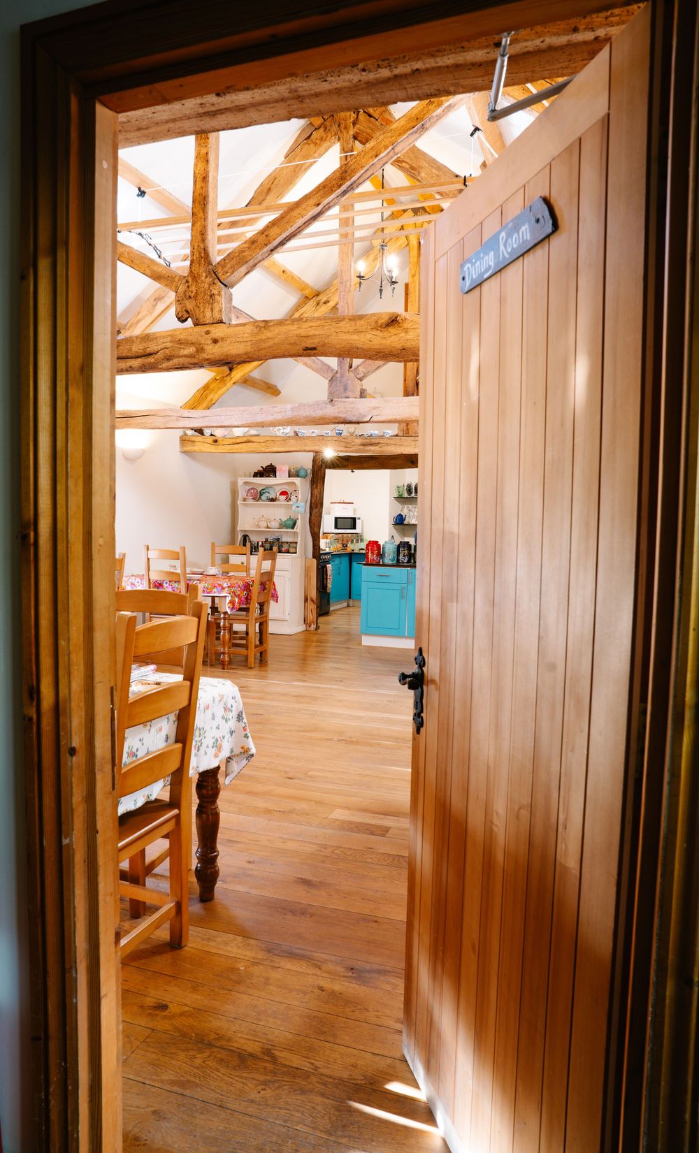Rustic interior doorway leading to a bright room with exposed wooden beams and hardwood floors.