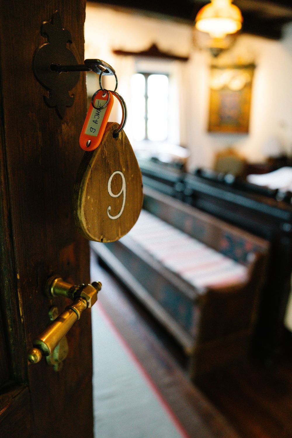 Room key with number 9 hanging on vintage wooden door in traditional building interior.