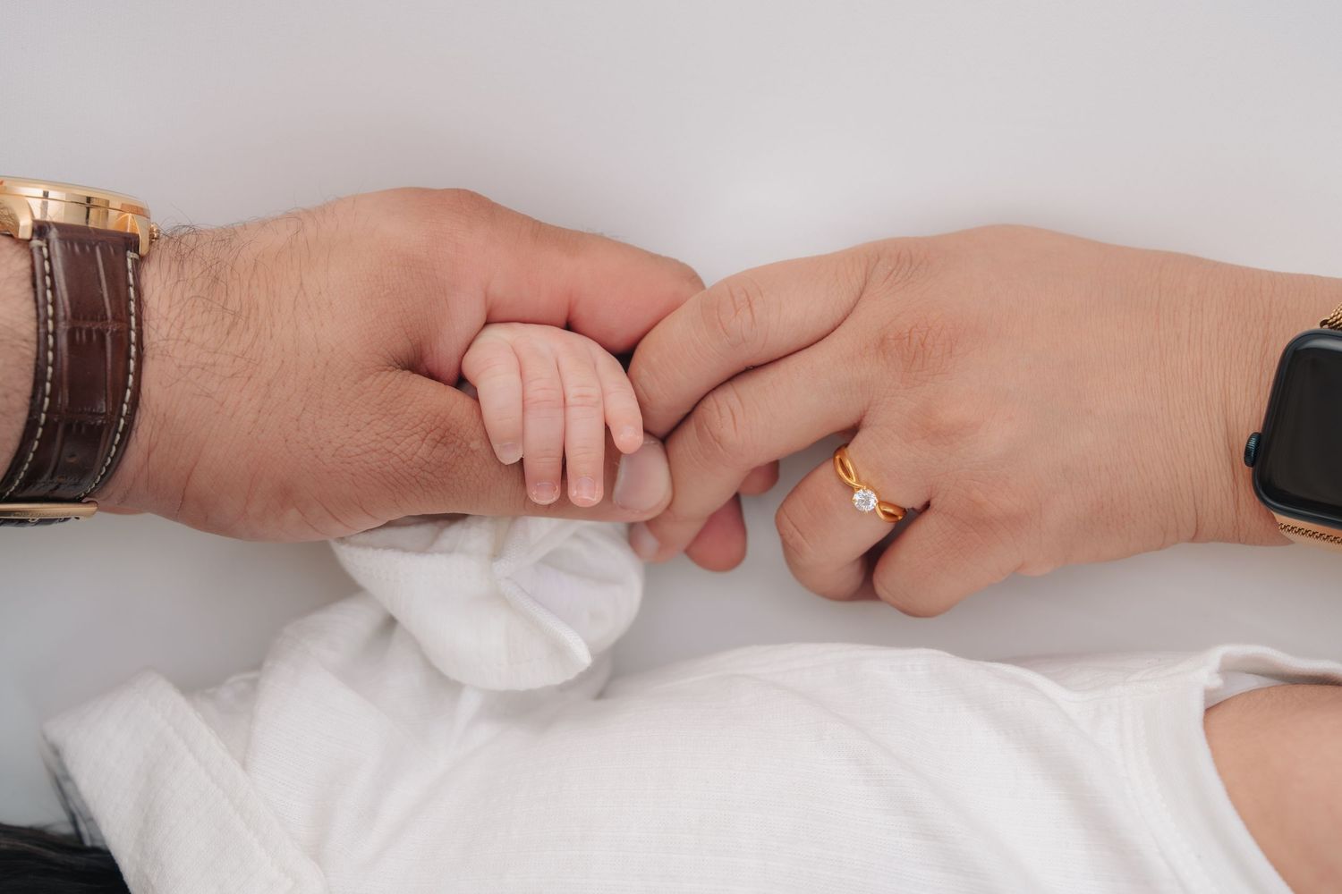 Close-up view of delicate baby hands grasping white fabric in a series of gentle poses.