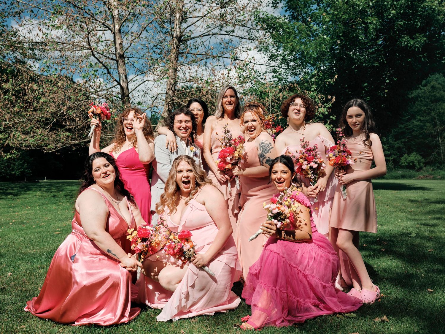 Candid group photo of groom laughing with bridesmaids in colorful dresses at Baltimore County wedding.