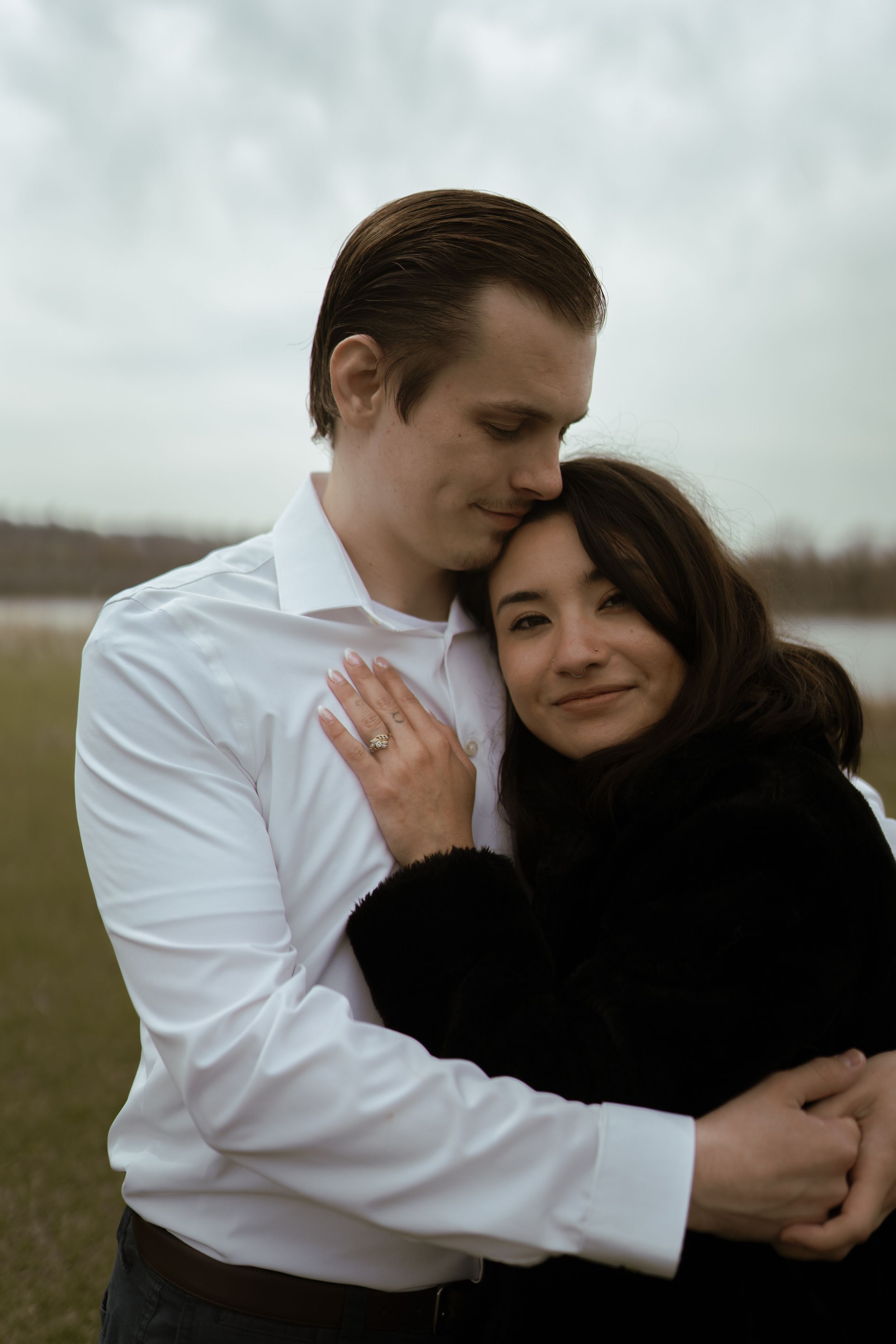 A tender embrace between two people wearing contrasting outfits against an overcast sky.