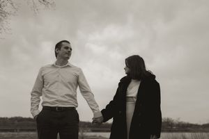 Two people in black and white clothing stand together in a serene landscape.