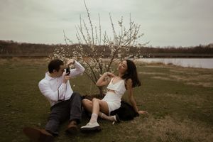 Playful couple shares drinks while relaxing outdoors.
