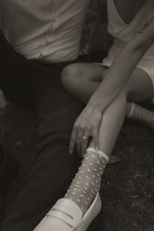 Close-up view of polka dot socks and casual footwear on grass during an outdoor photoshoot.