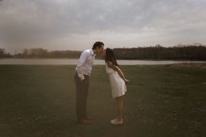 A couple playfully poses in an open field during golden hour.