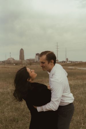 A couple shares a romantic dip pose with city buildings visible in the background.