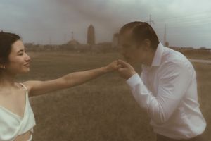 A romantic couple shares a tender moment with one person kissing the other's hand.