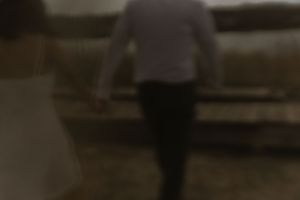Blurry artistic photo of a person walking on wooden planks near water.
