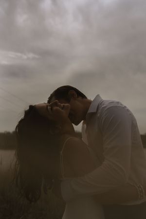 Silhouetted romantic moment between two people against a moody cloudy sky.