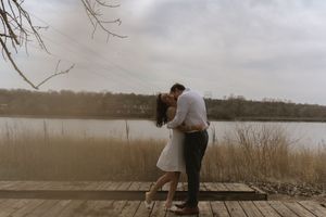 Couple sharing an intimate moment on a wooden dock overlooking a misty lake.