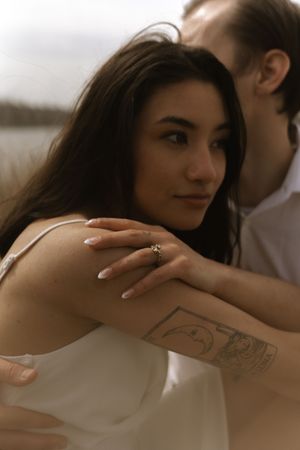 Close-up portrait showing a detailed tattoo on an arm with soft natural lighting.