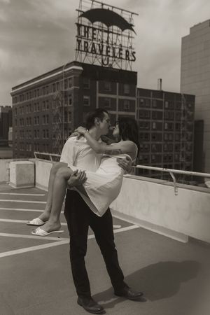 A black and white photo of a couple embracing on a rooftop parking deck near the Travelers building.