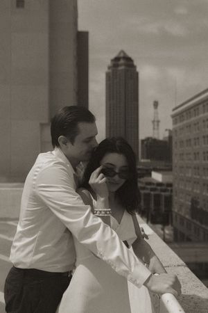 A romantic black and white portrait on a city rooftop with iconic buildings in the background.