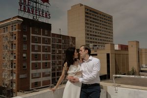 A tender moment captured between two people on a city rooftop with vintage signage visible.