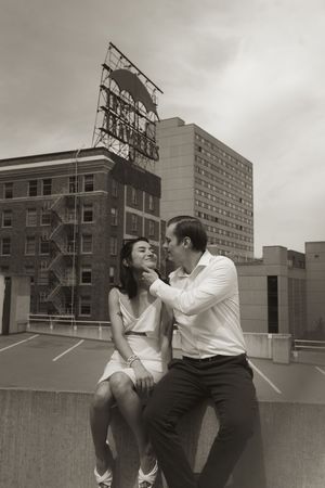 A romantic couple shares intimate moments on an urban rooftop with brick buildings in the background.