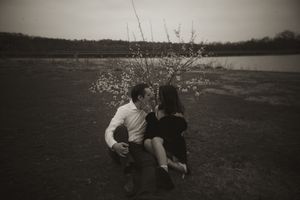 A couple embraces in a natural field setting during golden hour.