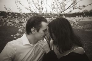 Intimate black and white portrait of a couple among spring tree branches.