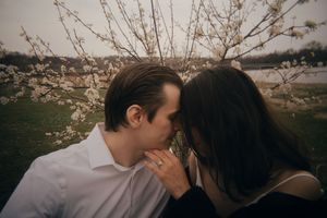 Romantic couple embracing under blooming cherry blossom trees at sunset.