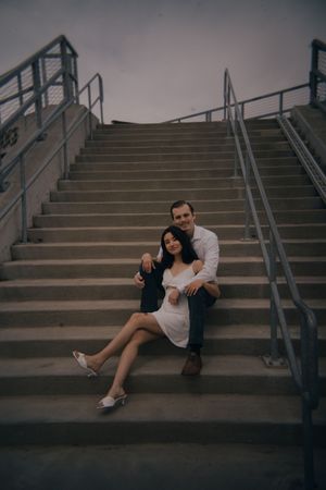Couple sitting together on concrete steps in urban setting at dusk.