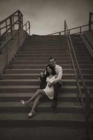 Black and white photo of couple relaxing on industrial staircase.
