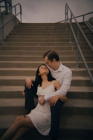 Intimate moment shared between couple on concrete steps during photo session.