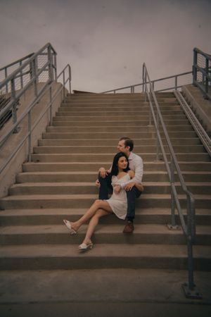 Artistic wide shot of couple sitting on urban staircase.