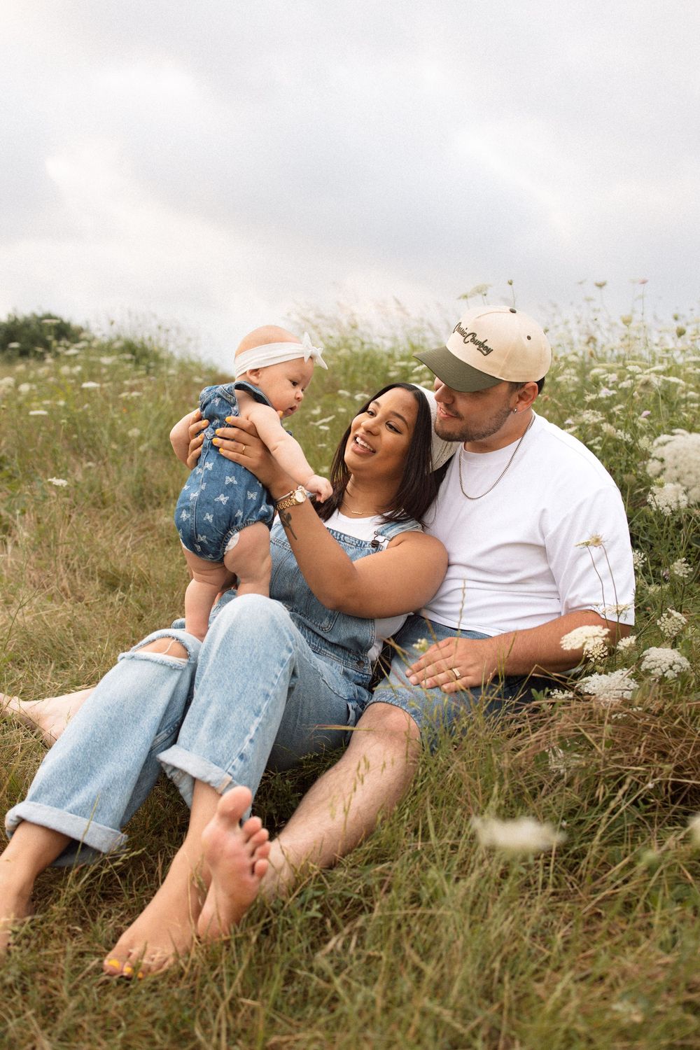 Family relaxing together in a wildflower meadow on a cloudy summer day.