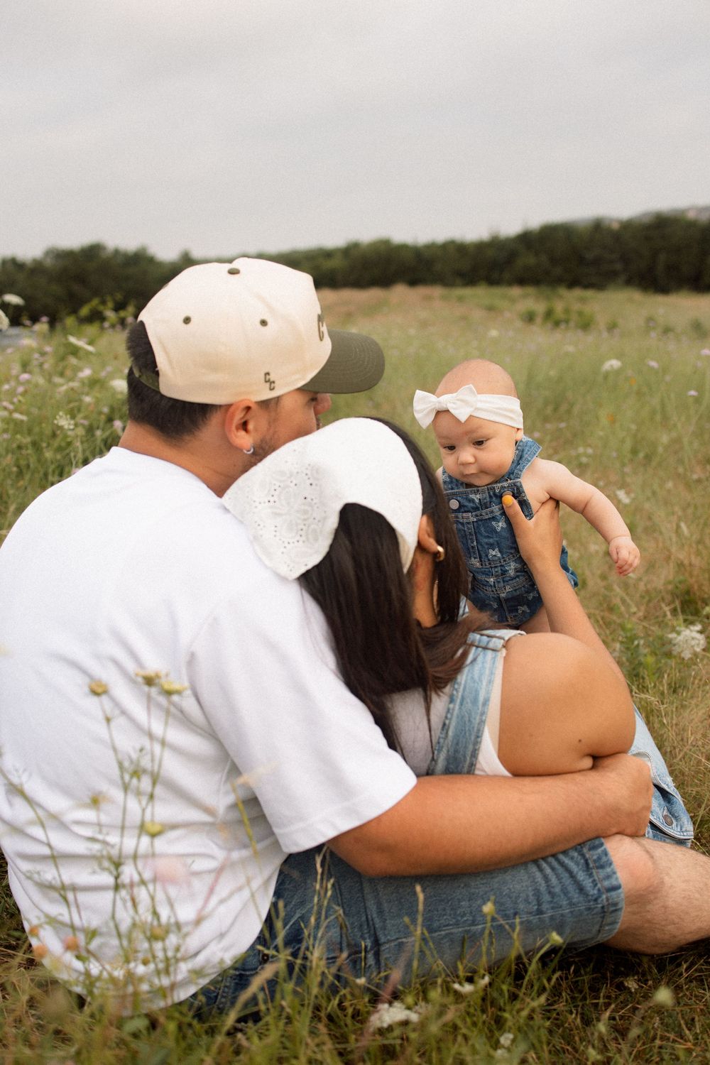 A family sits together in a wildflower meadow enjoying a warm summer afternoon.