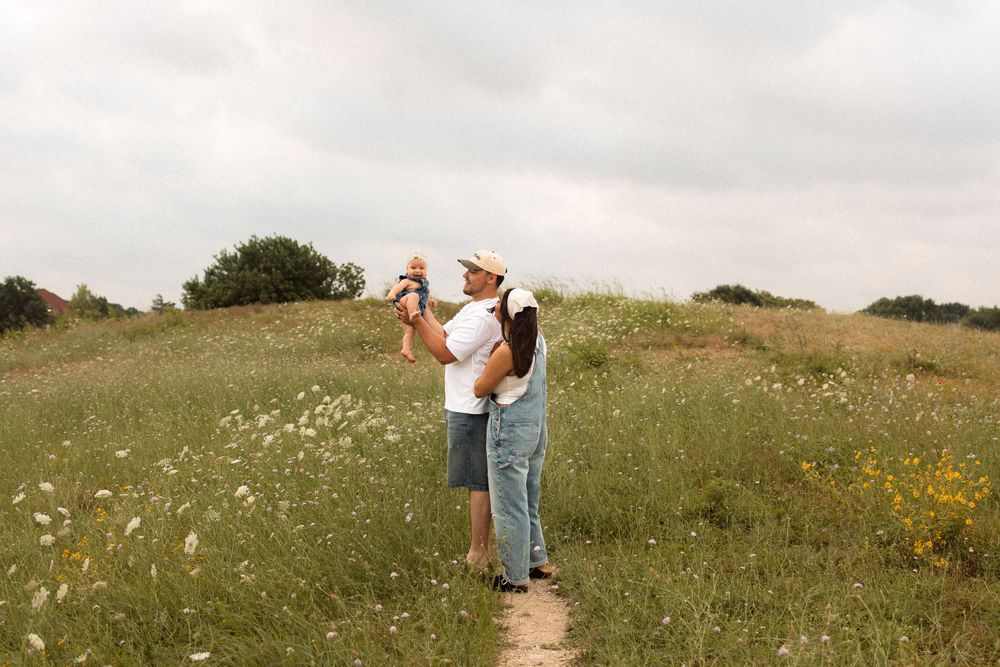 A couple shares a tender moment in a wildflower meadow on a summer afternoon.