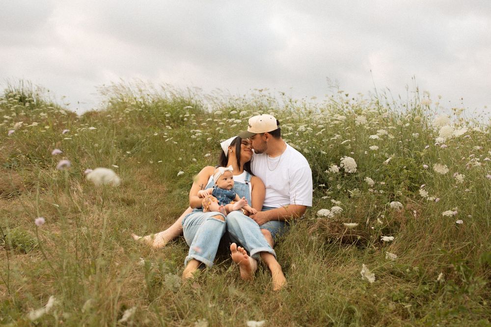 A couple sits in a wildflower meadow of white flowers on a summer afternoon, reading together.