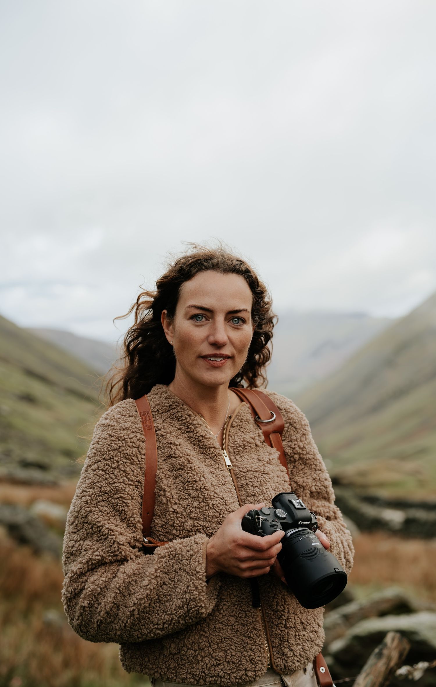 Anna Bailey Photography standing on a fell with her camera.