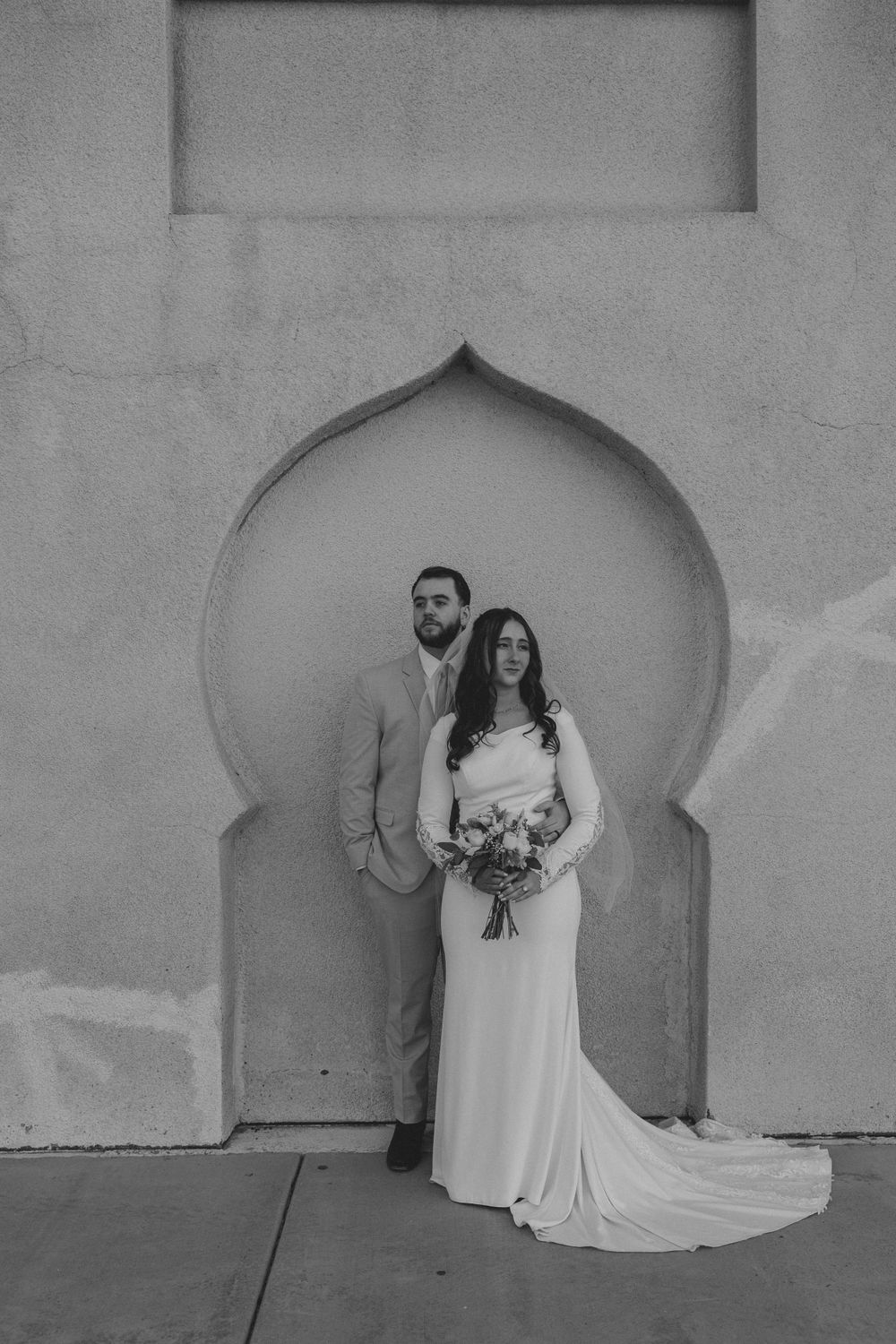 A stunning black and white architectural wedding portrait taken in front of an elegant arched Moroccan doorway.