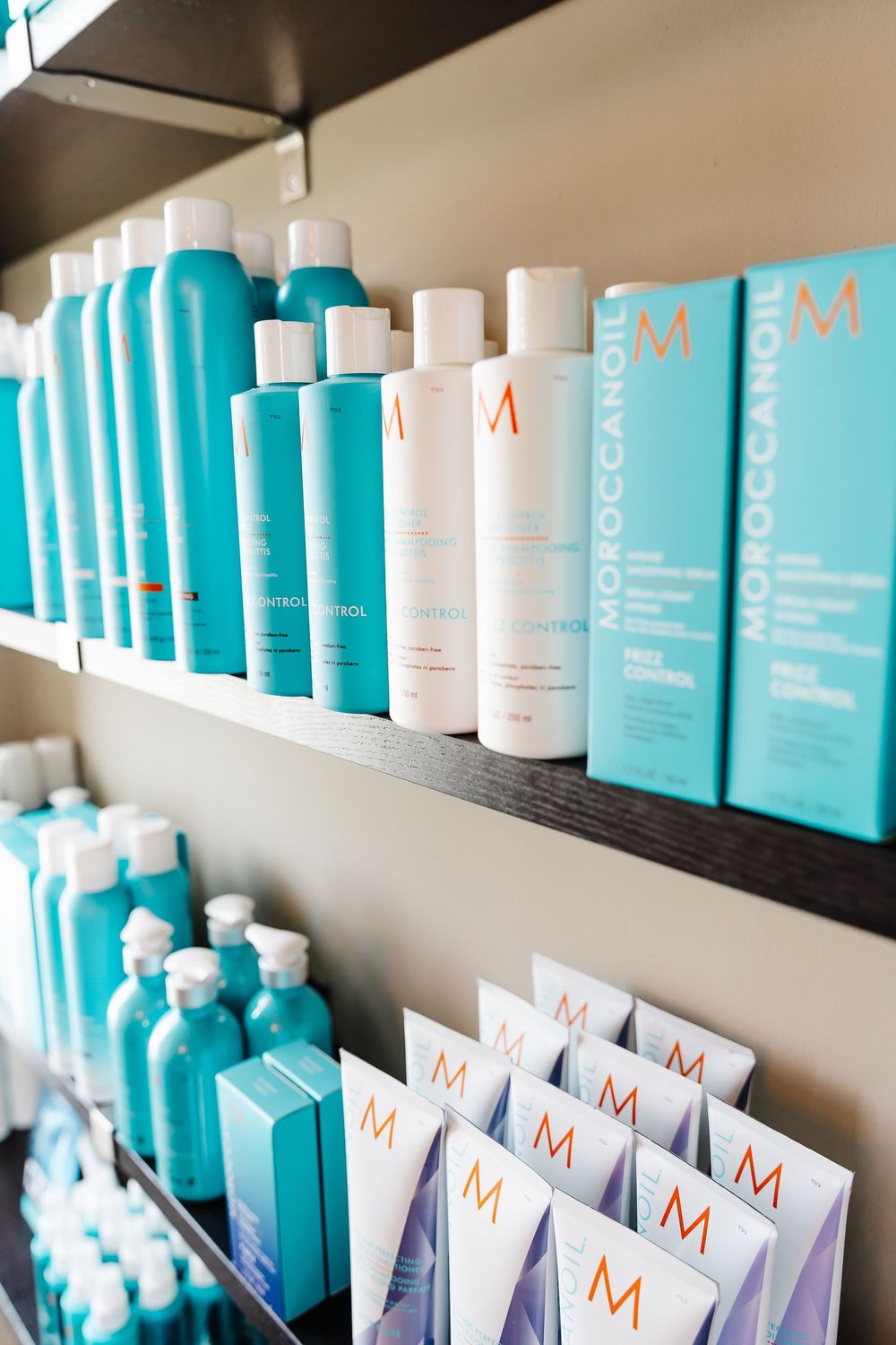 Display shelves stocked with Moroccanoil beauty products in signature turquoise blue and white packaging at a salon.