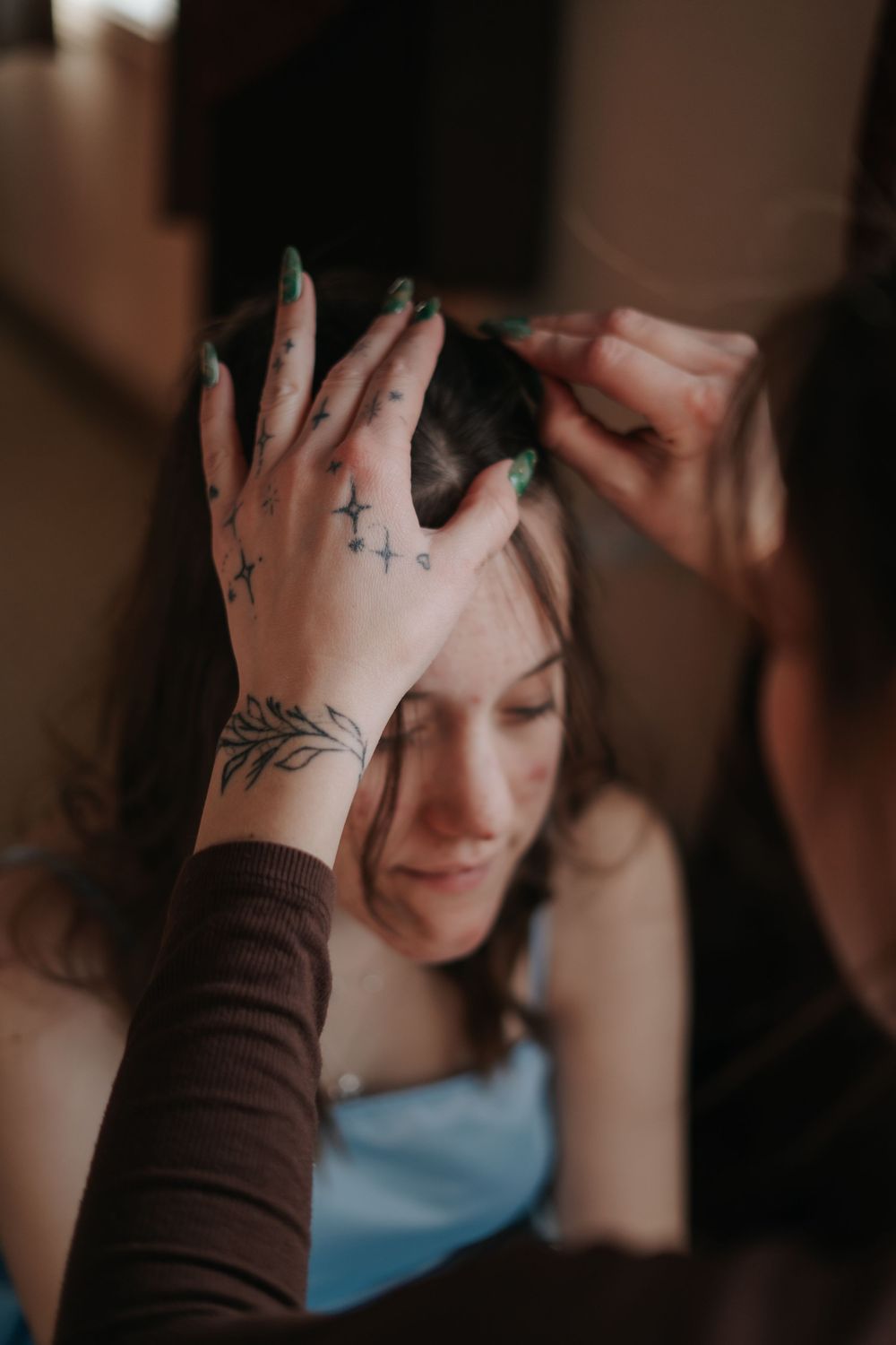A tattooed hand with delicate floral designs reaches up during a quiet moment of preparation.